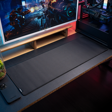 Load image into Gallery viewer, Large black Aftershock XL Glide cloth mousepad on a desk under a monitor and beside a gaming PC, stitched edges and small.